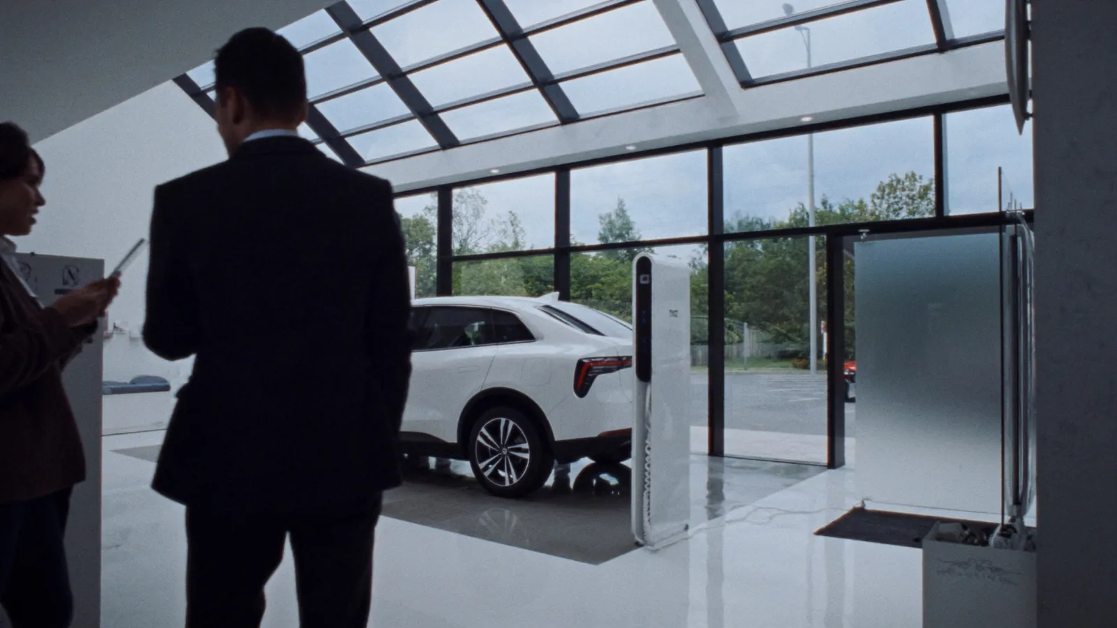 Autohaus-Showroom mit Elektroauto, DC-Ladesäule und Verkäufer